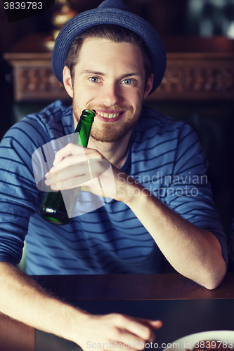 Image of happy young man drinking beer at bar or pub