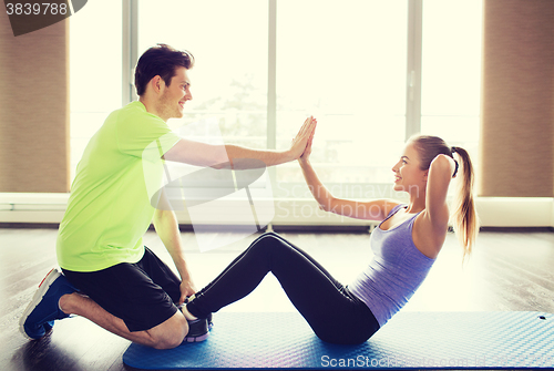 Image of woman with personal trainer doing sit ups in gym