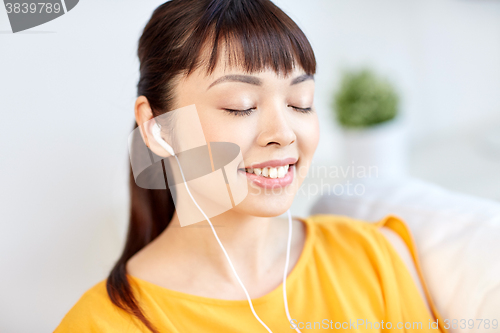 Image of happy asian woman with earphones listening music