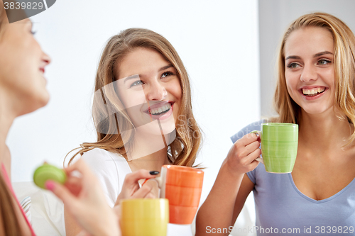 Image of happy young women drinking tea with sweets at home