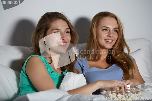 Image of happy friends with popcorn and watching tv at home