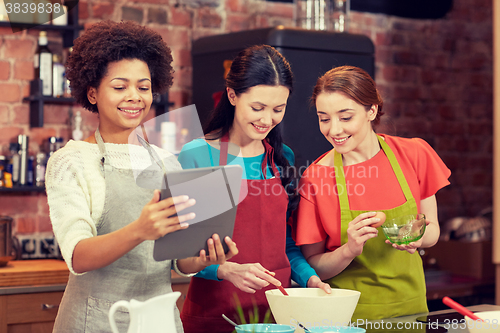 Image of happy women with tablet pc cooking in kitchen