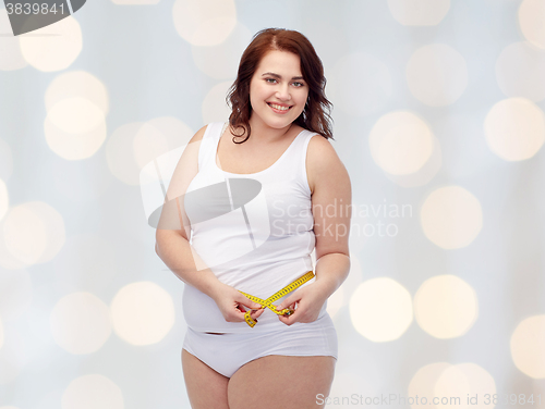 Image of happy young plus size woman with measuring tape