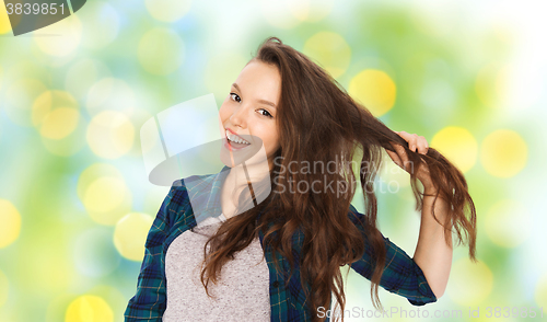 Image of happy teenage girl holding strand of her hair