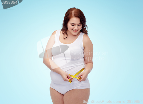 Image of happy young plus size woman with measuring tape