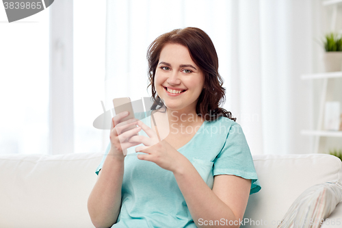 Image of happy plus size woman with smartphone at home