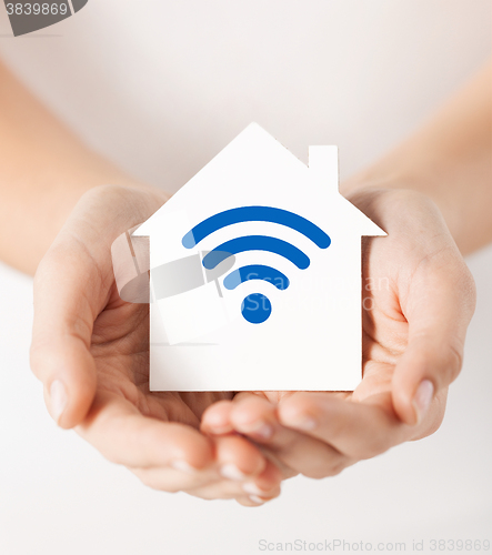 Image of hands holding house with radio wave signal icon