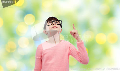 Image of happy little girl in eyeglasses pointing finger up