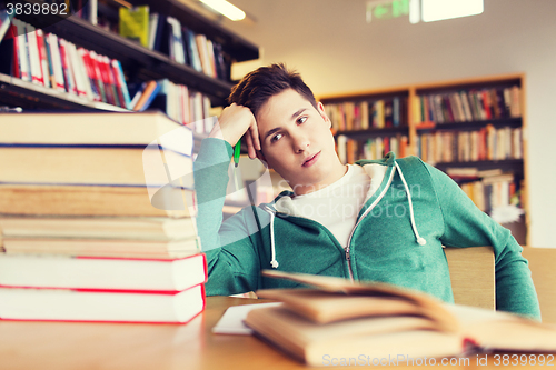 Image of bored student or young man with books in library