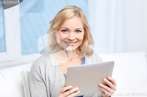 Image of happy middle aged woman with tablet pc at home