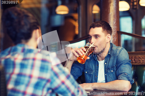 Image of happy male friends drinking beer at bar or pub