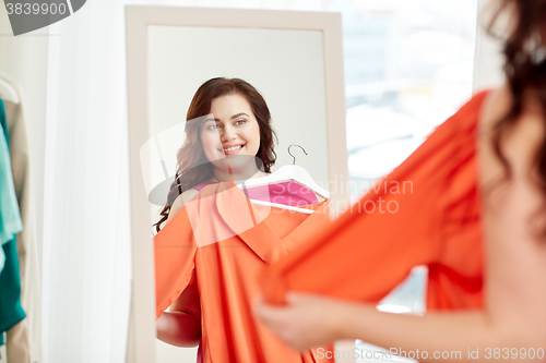 Image of happy plus size woman with shirt at mirror