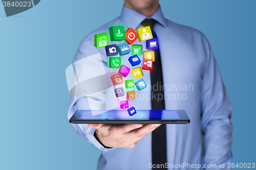 Image of Businessman holding a tablet pc with mobile applications icons on virtual screen . Internet and business concept.