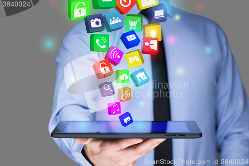 Image of Businessman holding a tablet pc with mobile applications icons on virtual screen . Internet and business concept.