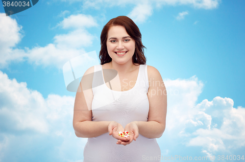 Image of happy plus size woman in underwear with pills