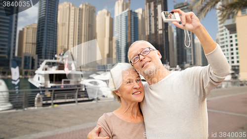 Image of senior couple taking selfie with camera at harbor