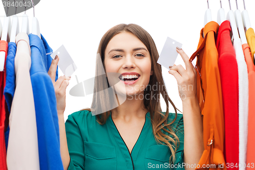 Image of happy woman with sale tags on clothes at wardrobe