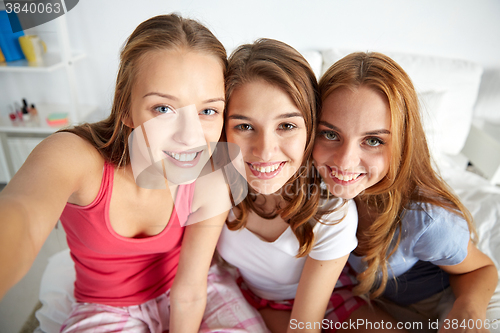 Image of happy friends or teen girls taking selfie at home