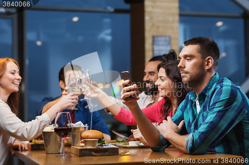 Image of man with smartphone and friends at restaurant