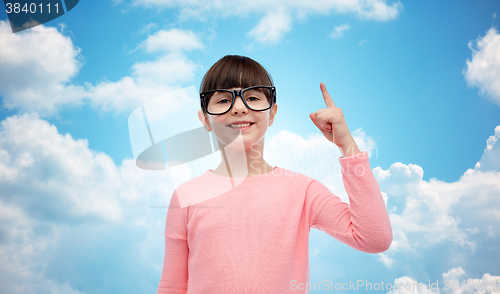 Image of happy little girl in eyeglasses pointing finger up