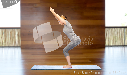 Image of woman making yoga in chair pose on mat