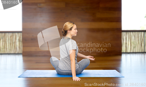 Image of woman making yoga in twist pose on mat