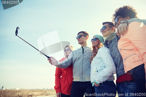 Image of smiling friends taking selfie with smartphone