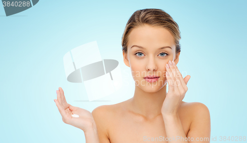Image of young woman applying cream to her face