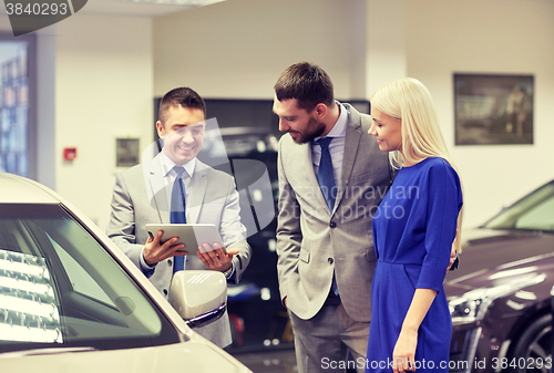 Image of happy couple with car dealer in auto show or salon