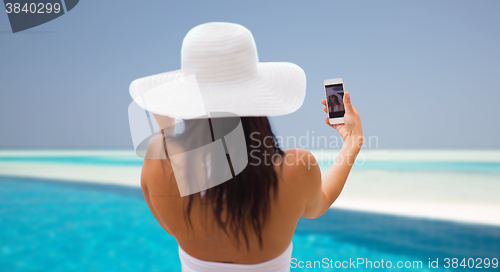 Image of smiling young woman taking selfie with smartphone