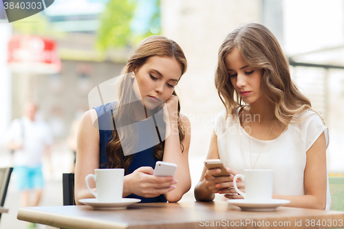 Image of women with smartphones and coffee at outdoor cafe