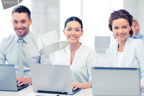 Image of group of people working with laptops in office