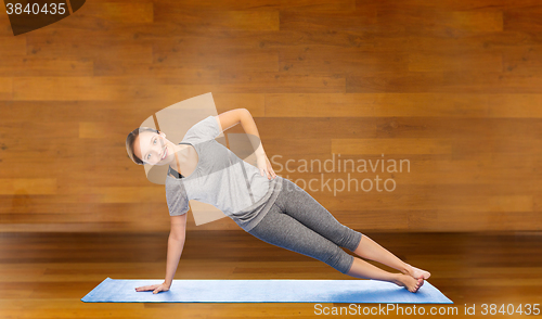 Image of woman making yoga in side plank pose on mat