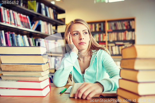 Image of bored student or young woman with books in library