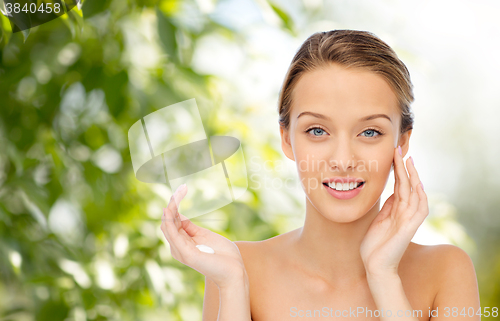 Image of happy young woman applying cream to her face