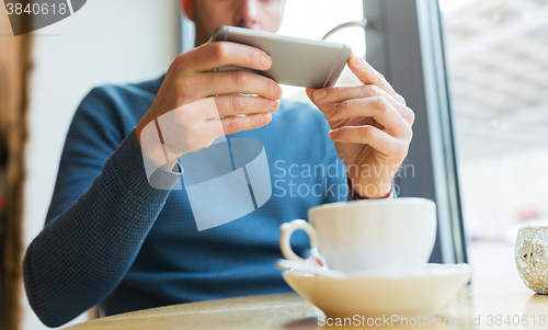Image of close up of man with smartphones at cafe