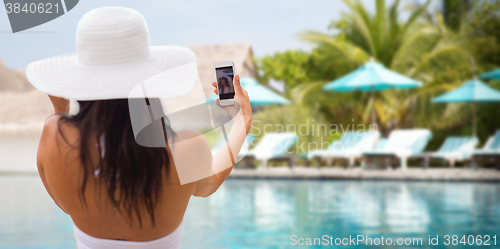 Image of smiling young woman taking selfie with smartphone