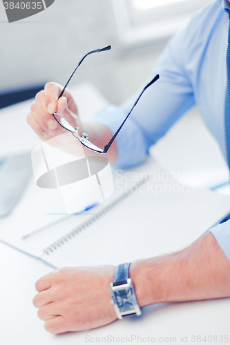 Image of businessman with spectacles writing in notebook