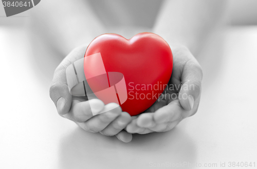 Image of close up of child hands holding red heart