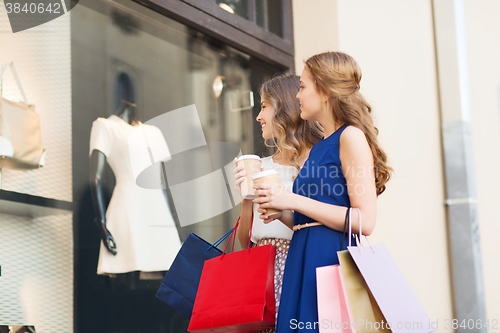 Image of young women with shopping bags and coffee at shop