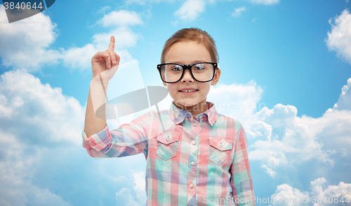 Image of happy little girl in eyeglasses pointing finger up