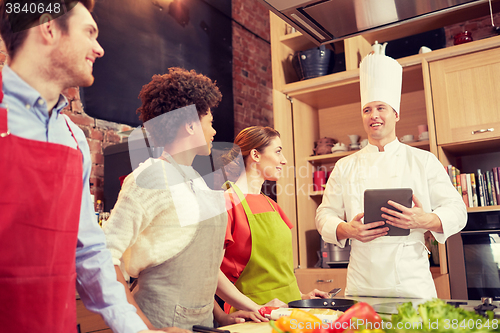 Image of happy friends with tablet pc in kitchen