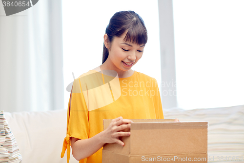 Image of happy asian young woman with parcel box at home