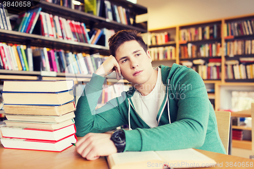 Image of bored student or young man with books in library