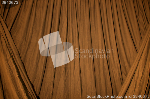 Image of Draped black background cloth lit with orange gel