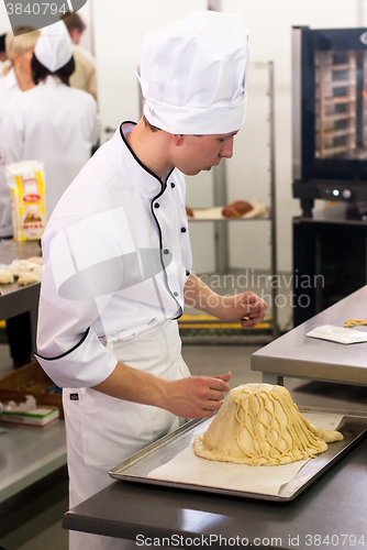 Image of Young cook prepares food in competition