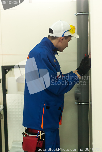 Image of Young plumber installs equipment for bathroom