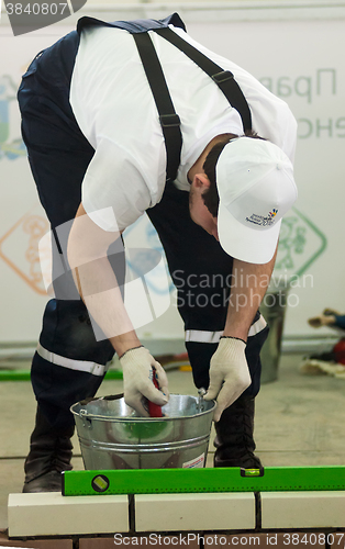 Image of Young bricklayer performs a task of competition