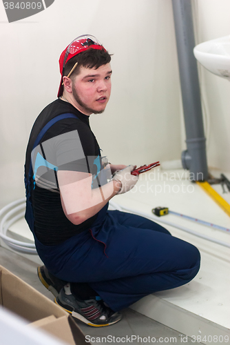 Image of Young plumber installs equipment for bathroom