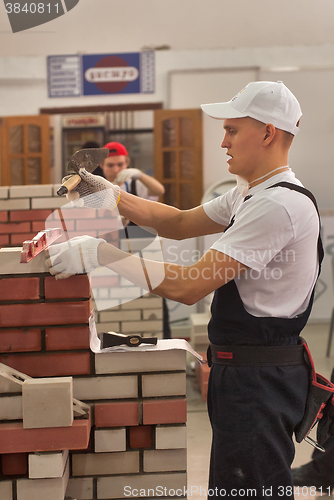 Image of Young bricklayer performs a task of competition